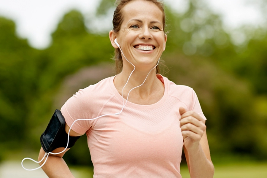 woman jogging with earbuds and phone on arm
